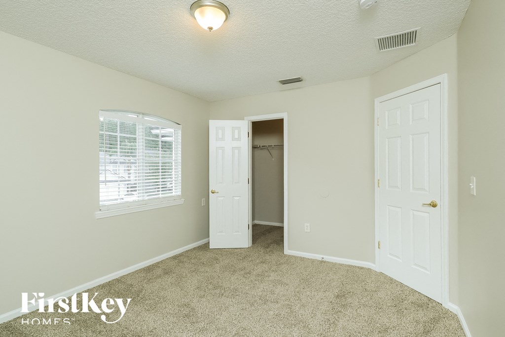 a bedroom with a carpeted floor and a door to a closet