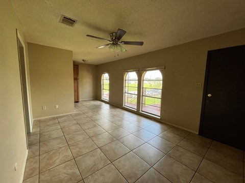 A spacious room with a ceiling fan and large windows.