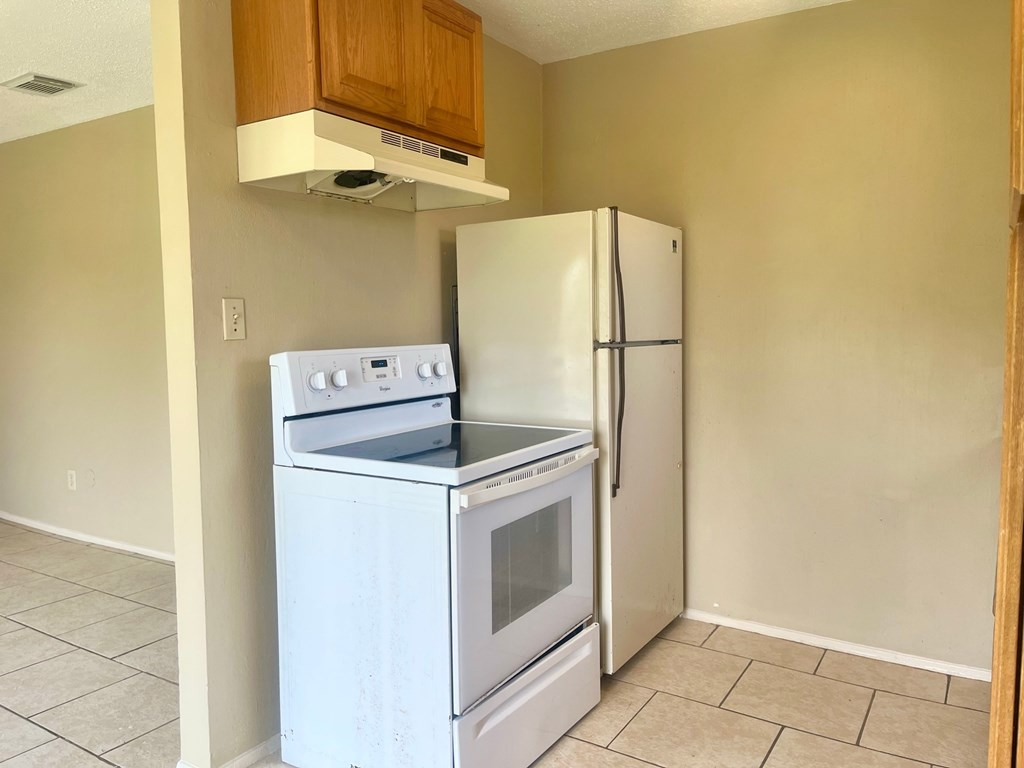 an empty kitchen with a stove and refrigerator