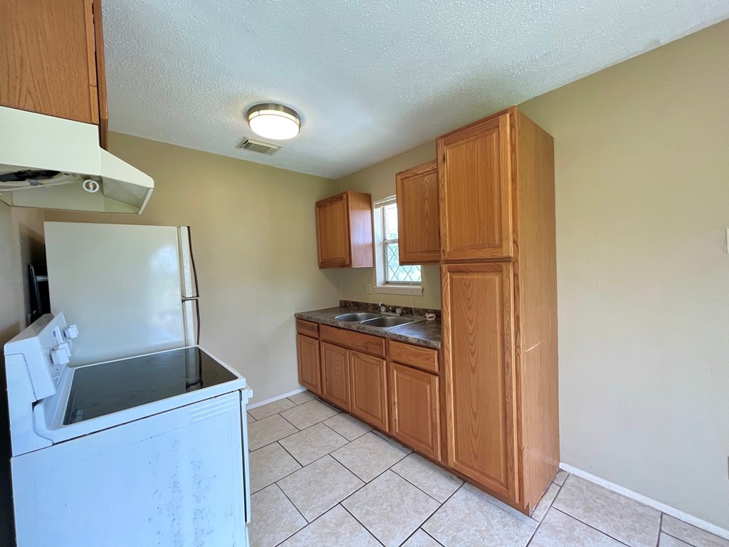 an empty kitchen with a stove refrigerator and sink
