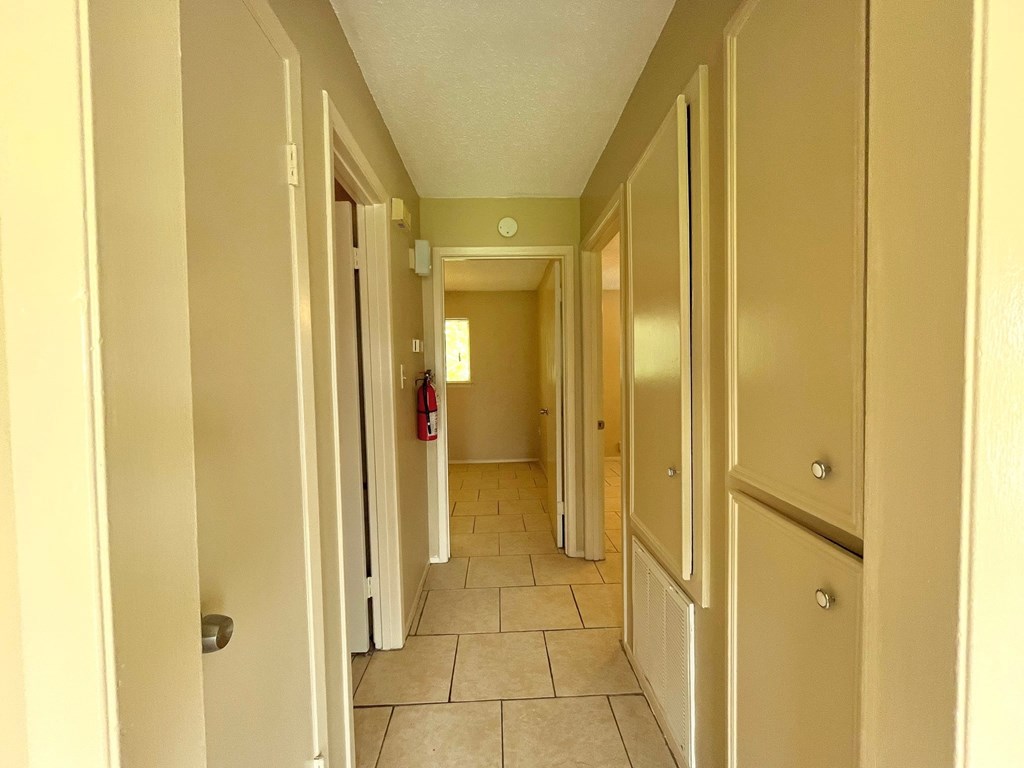 a hallway with white cabinets and a tiled floor