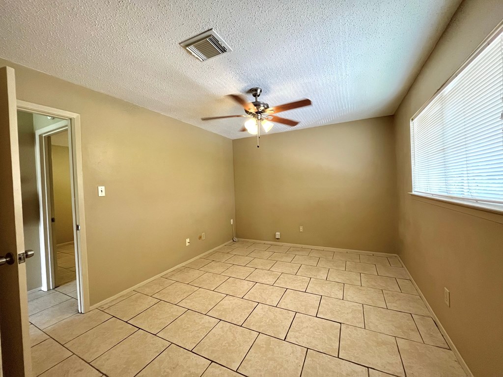 an empty living room with a ceiling fan and tiled floors