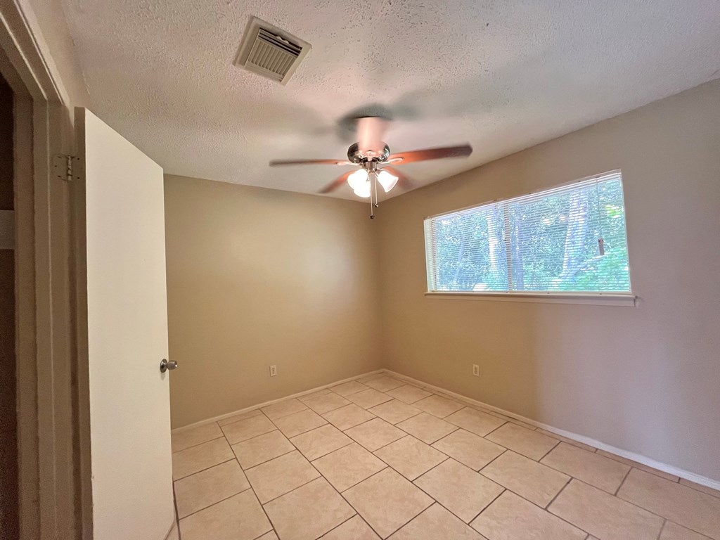 an empty living room with a ceiling fan and a window
