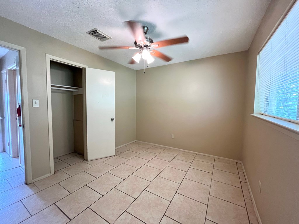 an empty living room with a ceiling fan and tiled floors