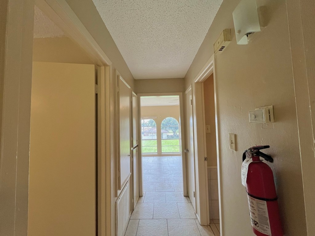 a hallway with a fire extinguisher on the wall and a door to a room