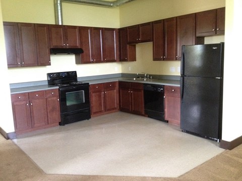 an empty kitchen with black appliances and wooden cabinets