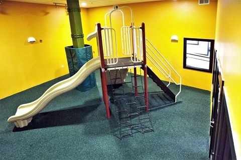 a playground with a slide and stairs in a building
