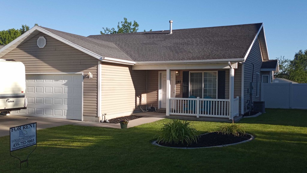 A house with a sign that says "For Rent" in front of it.