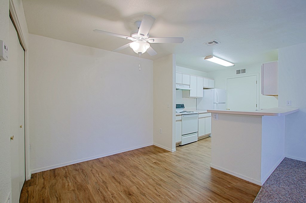 an empty living room and kitchen with a ceiling fan