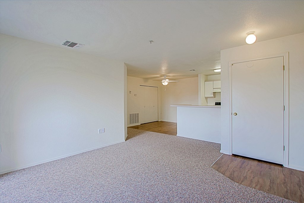 an empty living room and kitchen with white walls and flooring