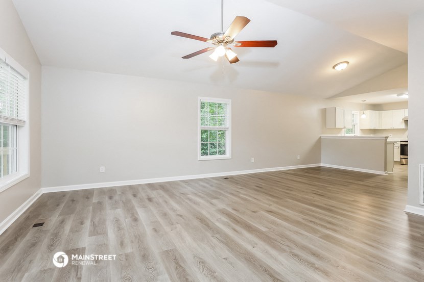 the living room and dining room with wood flooring and a ceiling fan