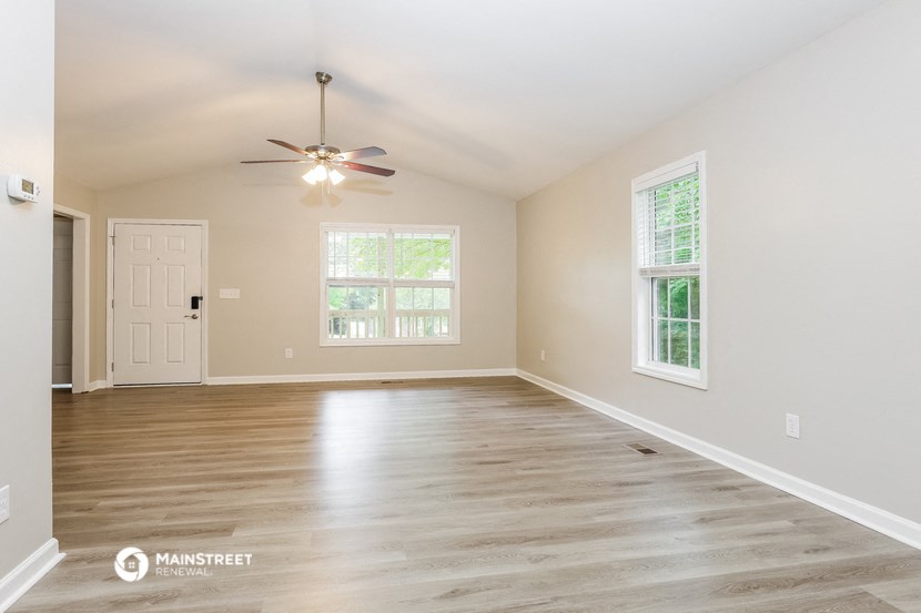 an empty living room with a ceiling fan and a window