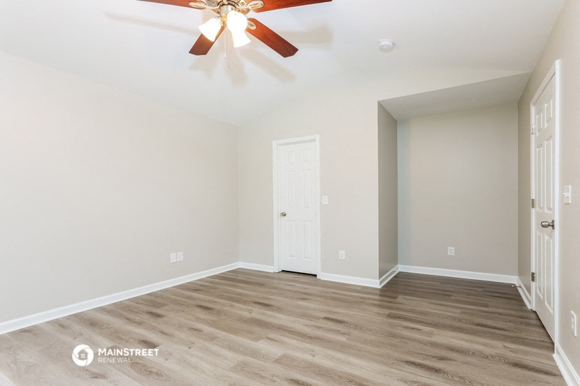 the living room of an empty house with a ceiling fan