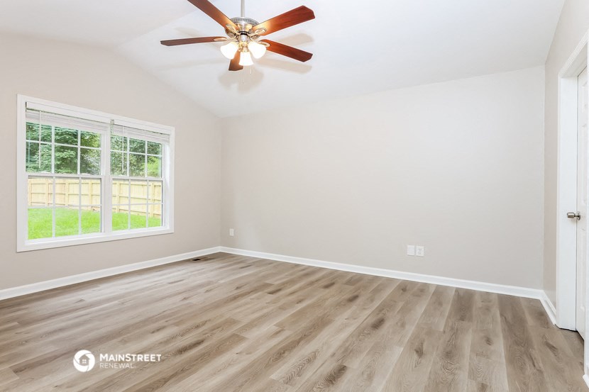 the living room of a home with wood floors and a ceiling fan