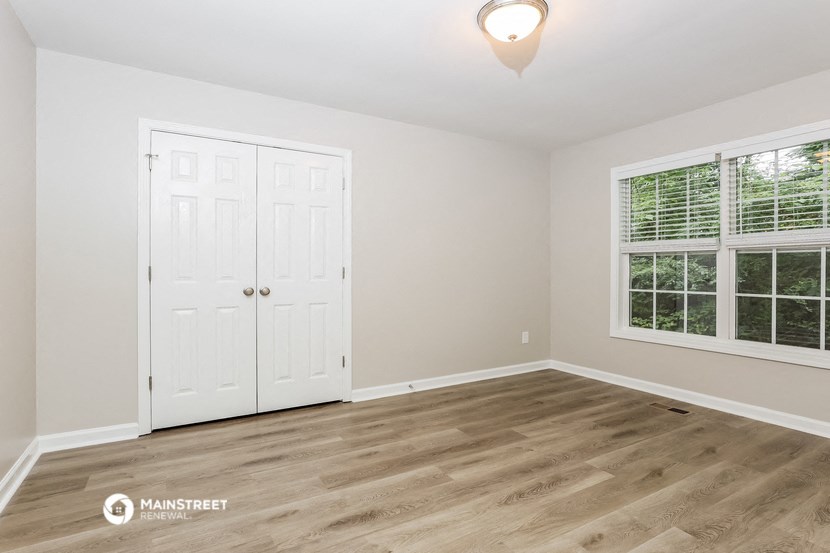 an empty bedroom with white doors and a window