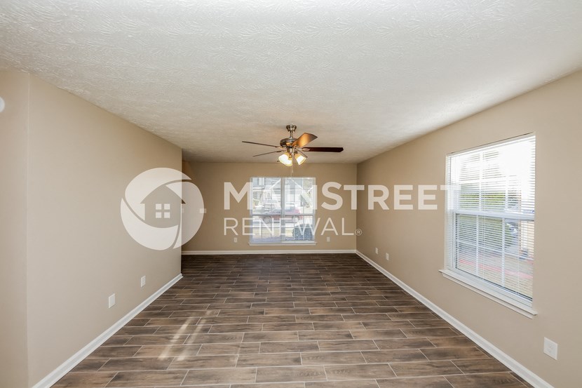 a spacious living room with a ceiling fan and a large window