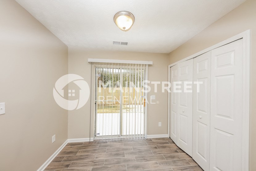 a bedroom with two closets and a large window and a door to a hallway