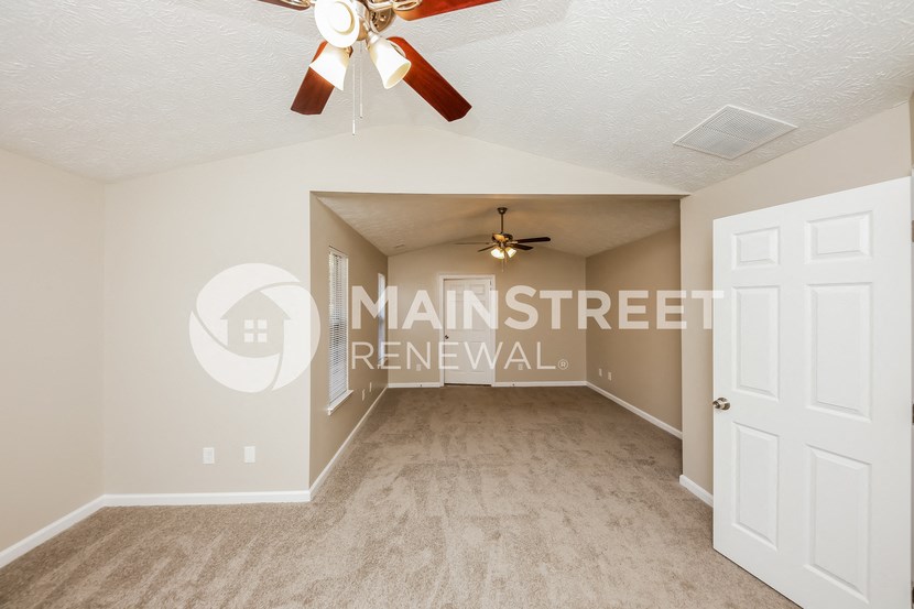 a spacious living room with a ceiling fan and a closet
