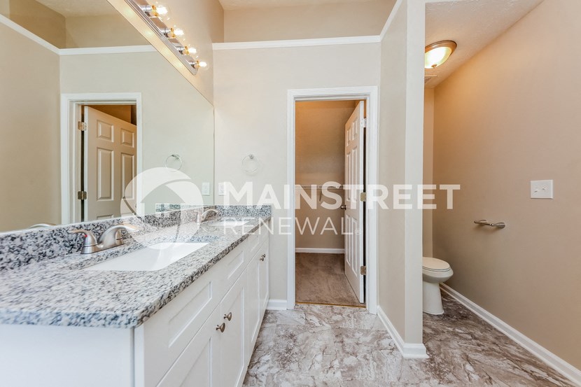a white bathroom with a marble counter top and a toilet