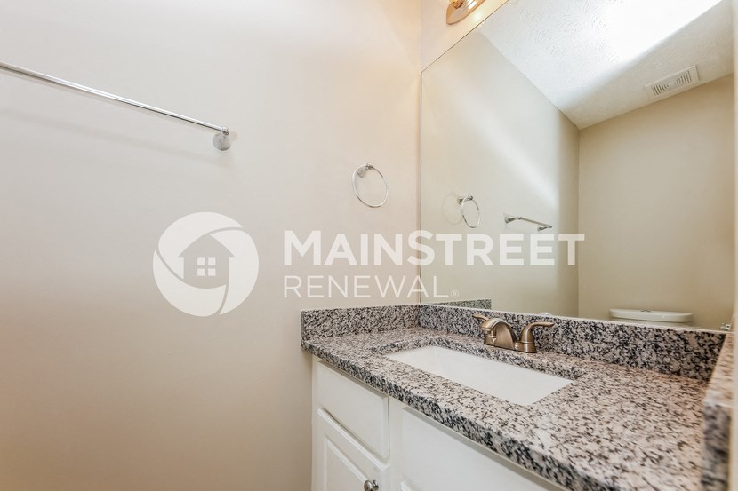 a bathroom with granite counter top and a sink