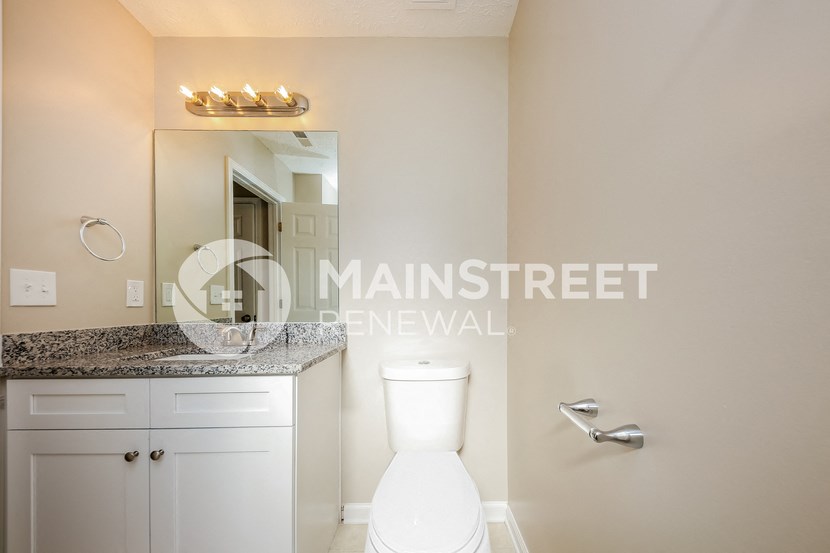 a bathroom with a white toilet and sink and a large mirror