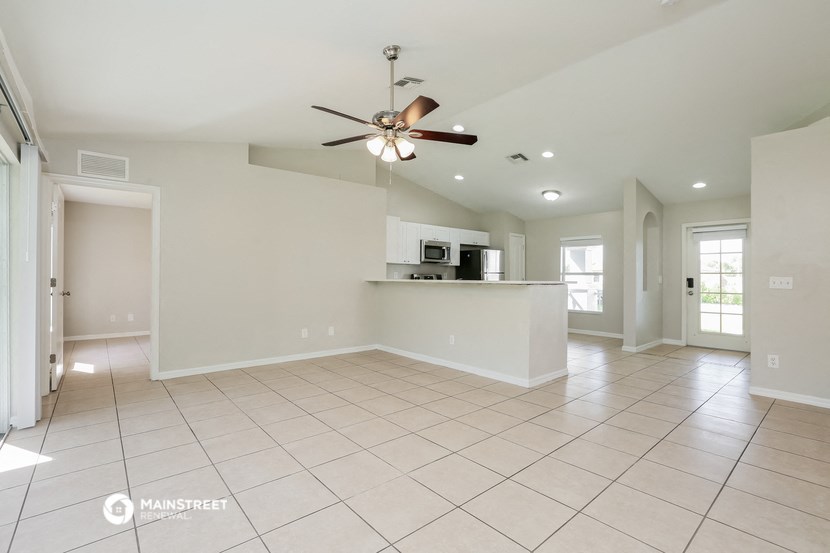 an empty kitchen and living room with a ceiling fan
