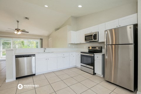 a large kitchen with white cabinets and stainless steel appliances
