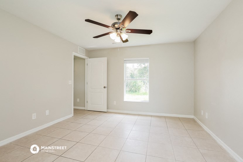 the spacious living room with ceiling fan and tiled floor