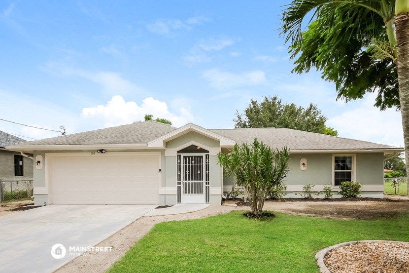 a white house with a driveway and a palm tree