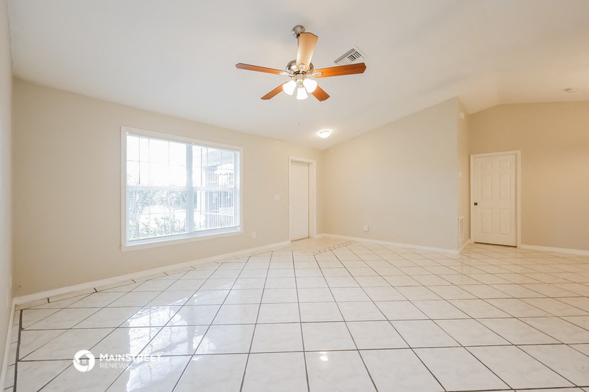 the spacious living room with tile flooring and a ceiling fan
