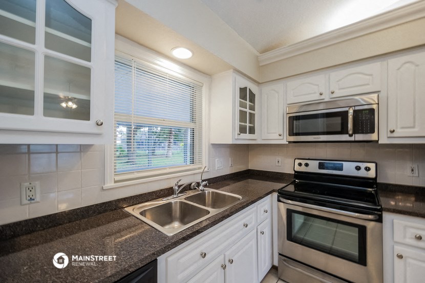 a kitchen with white cabinets and granite counter tops and a sink