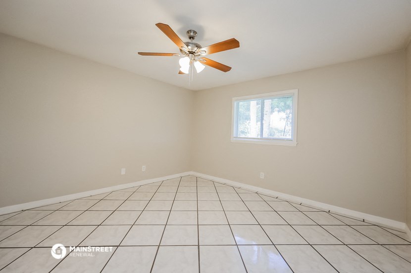 the spacious living room with tiled floors and a ceiling fan