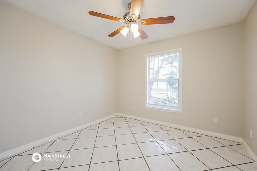 the living room of an empty home with a ceiling fan