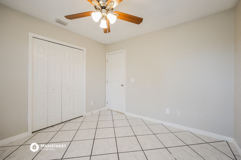 the living room of a home with a ceiling fan and tiled floor