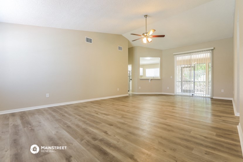the spacious living room with hardwood floors and a ceiling fan