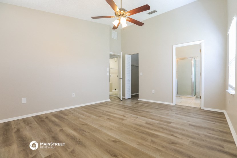 an empty living room with wood floors and a ceiling fan