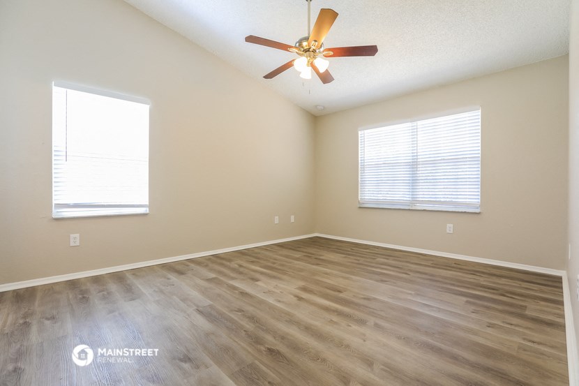 the spacious living room with hardwood floors and a ceiling fan