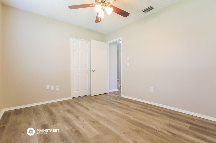 the spacious living room with hardwood floors and a ceiling fan