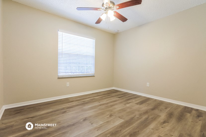 the spacious living room with hardwood floors and a ceiling fan