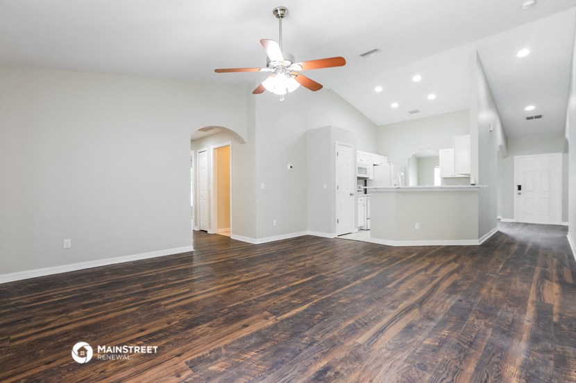 the living room and kitchen with wood flooring and a ceiling fan