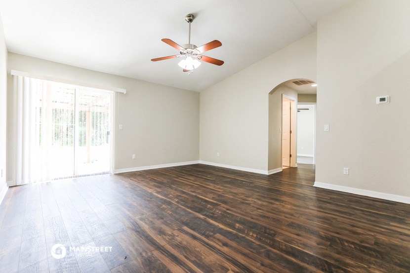 an empty living room with wooden floors and a ceiling fan