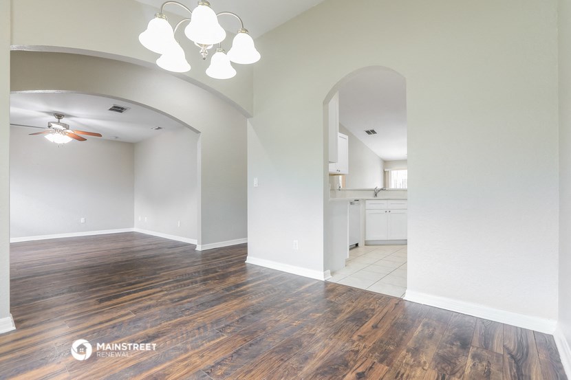 an empty living room with wood flooring and a kitchen