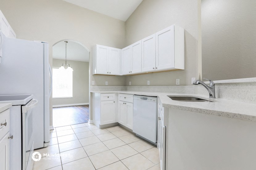 a kitchen with white cabinets and a sink and a refrigerator