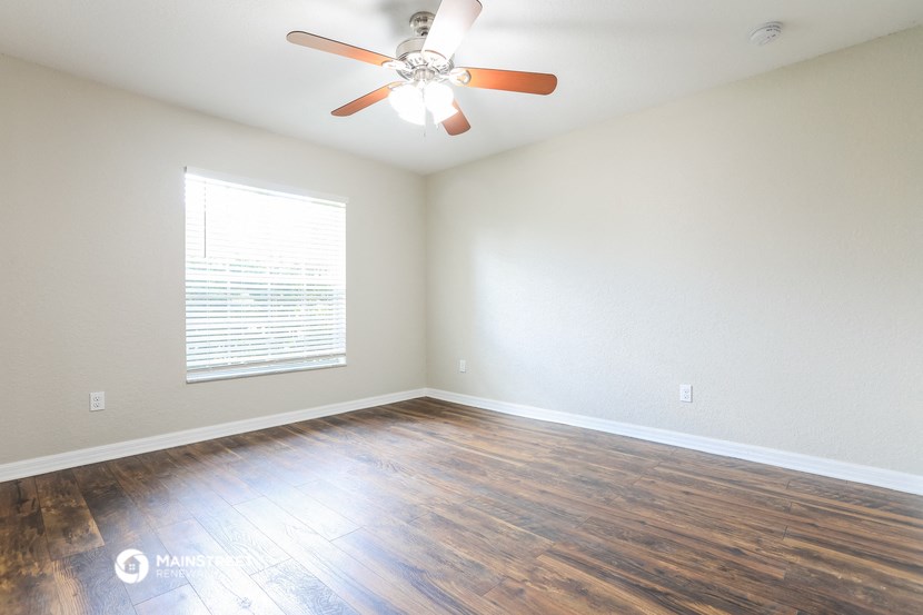an empty living room with wood floors and a ceiling fan