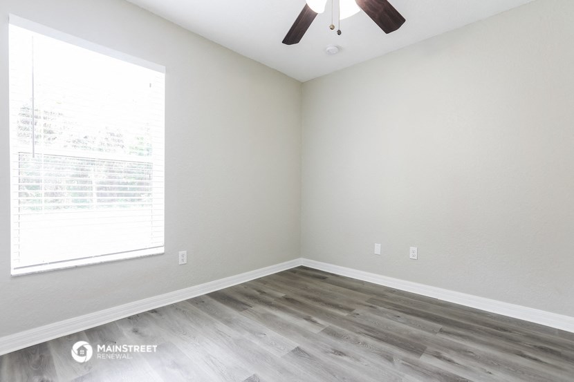 an empty room with wood floors and a window