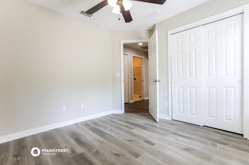 an empty living room with white doors and a ceiling fan