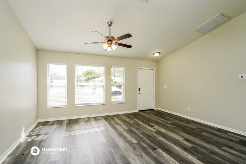 the living room of an empty house with a ceiling fan