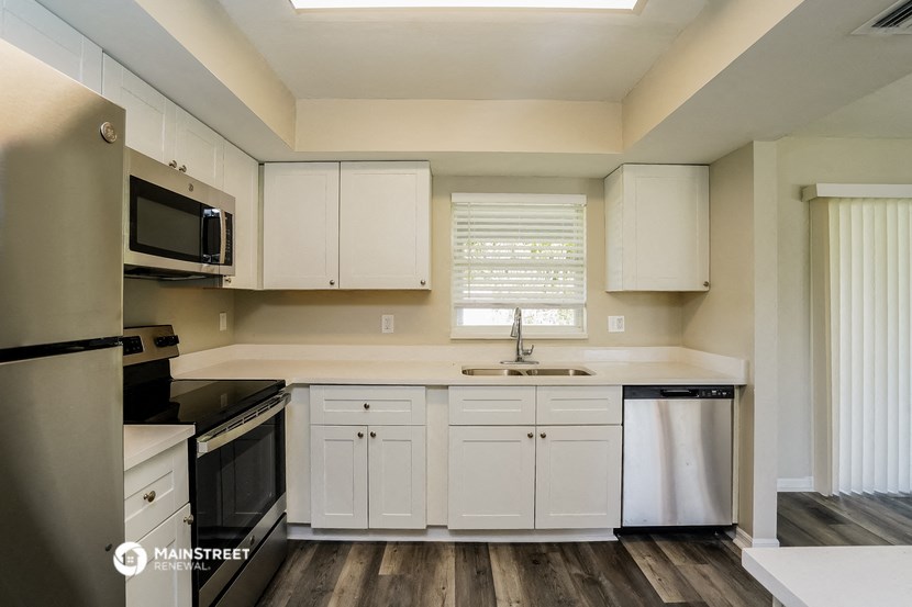 a kitchen with white cabinets and a sink and a refrigerator