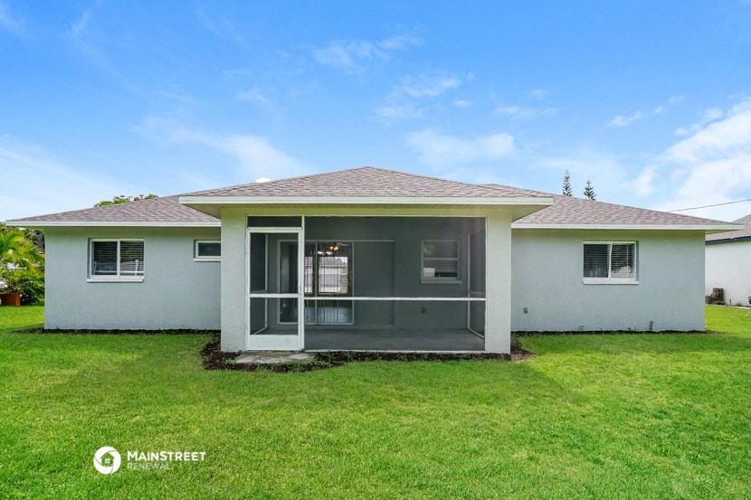 a small white house with a grass yard and a patio