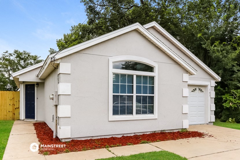 a small white house with a large window and a driveway